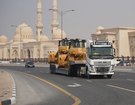 Lowbed trailer carrying heavy equipment on a UAE road